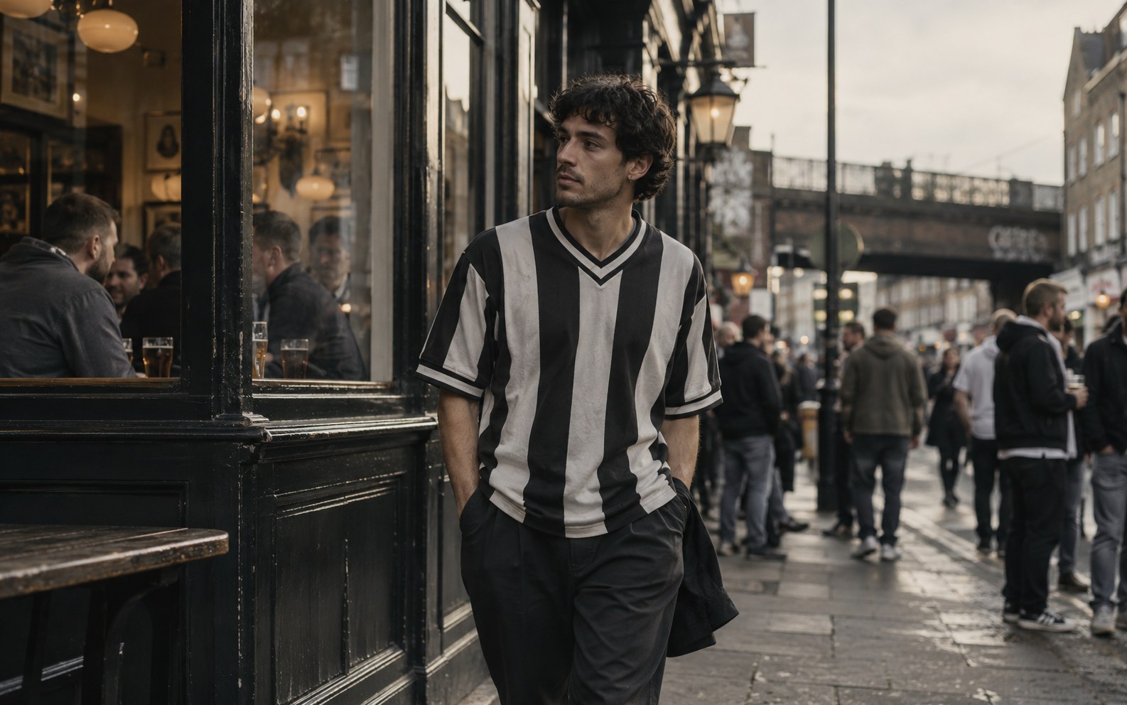 A person in a black-and-white football shirt on a city street outside a football pub on matchday.